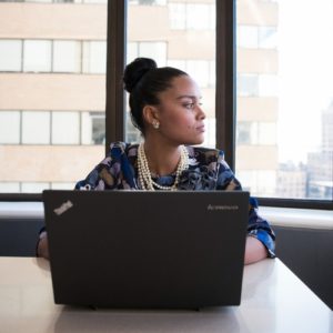 Woman absentmindedly looking away from computer, not focused