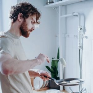 Man focused on making pancakes mindfully in a white kitchen