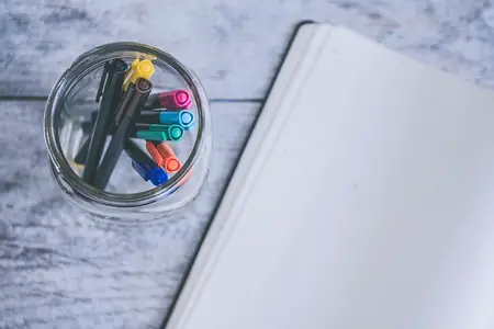 open journal with jar full of colored pens