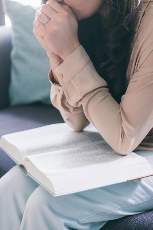 Woman praying with open Bible